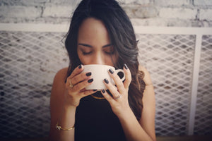 A young woman savoring a cup of coffee.