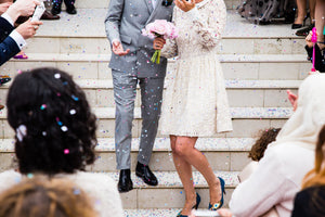 A newly married couple with a crowd cheering and throwing confetti.