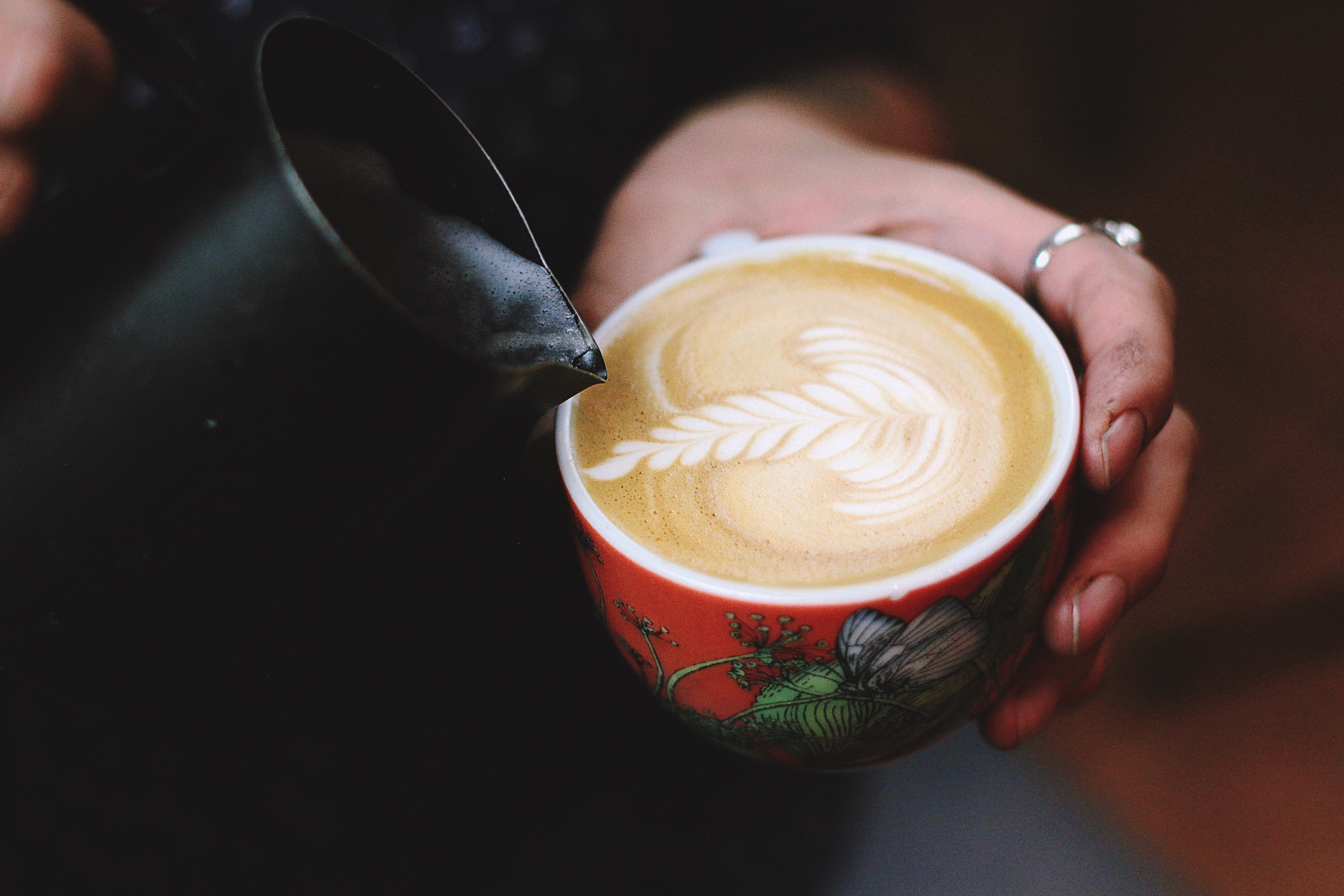 Pouring latte art on a flat white drink.